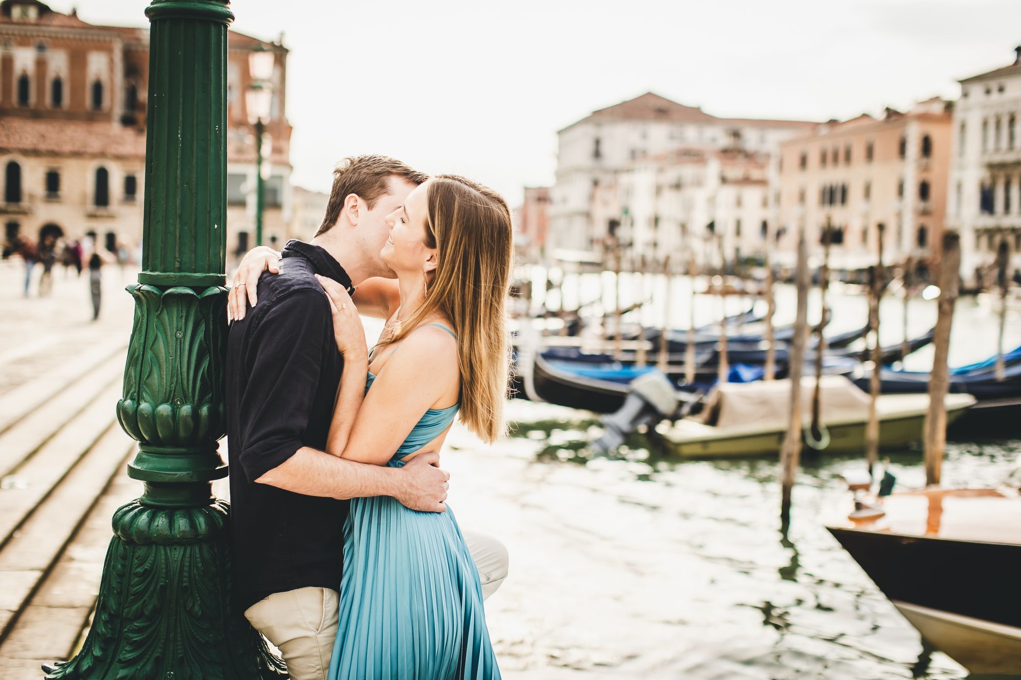 A couple sharing a kiss beside the gondolas in Venice, Italy